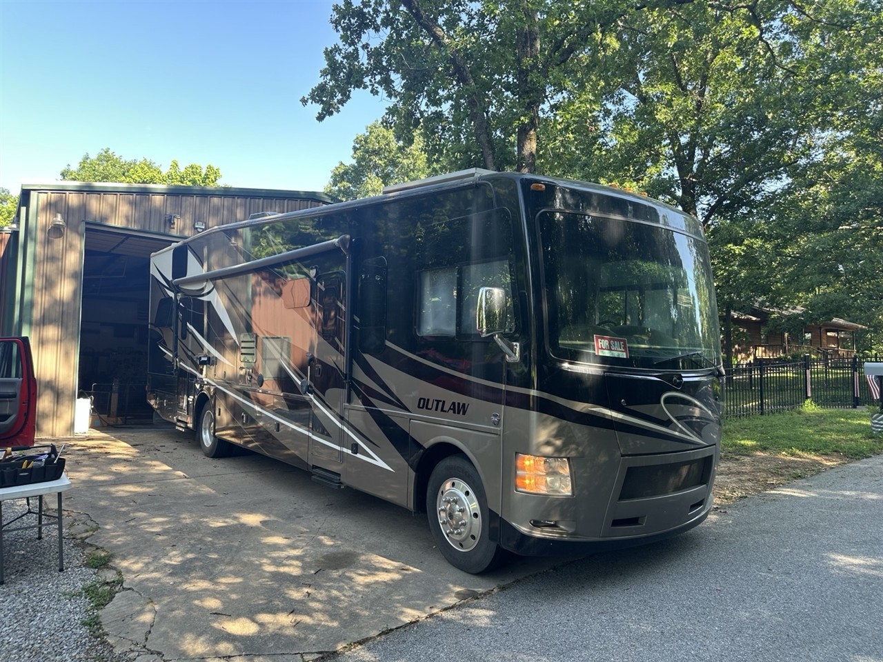 A toy hauler RV parked outside a garage