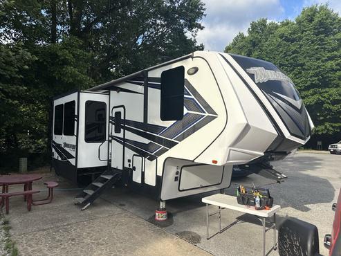 A toy hauler fifth wheel parked at a campground